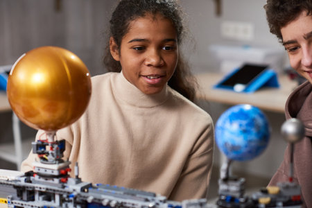 Portrait of black teenage girl building robots while enjoying engineering and robotics class in...