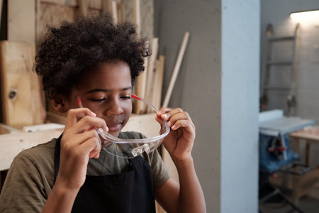 Portrait of cute black boy wearing protective glasses while helping dad in carpentry workshop, copy spaceの写真素材