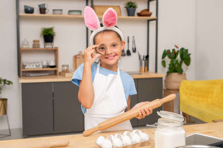 Close-up shot of little girl searching for salad recipe on digital tablet while standing at wooden...