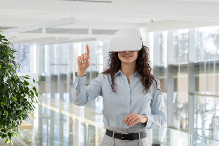 Happy young contemporary gaming developer in vr headset pointing at virtual screen while making presentation of new high tech spaceの写真素材