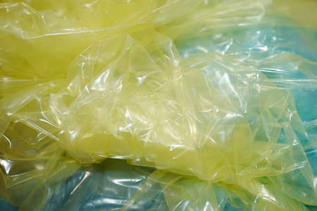 Part of crumpled cellophane of yellow color prepared for wrapping small metallic details of...