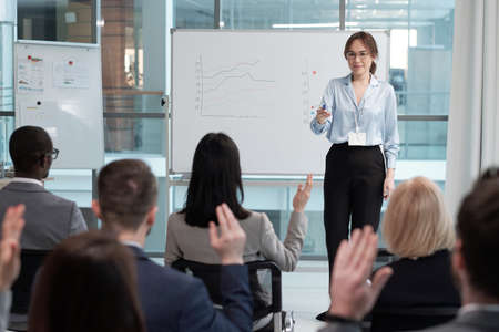 Confident speaker or business coach asking audience questions at seminar after presentation of...