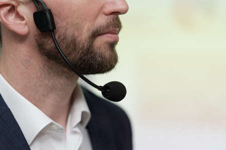 Close-up of lower part of face of young serious businessman with microphone under his chin against white backgroundの写真素材