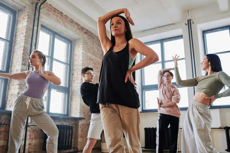 Contemporary female performer in activewear keeping right arm over her head while learning new movements of vogue dancingの写真素材
