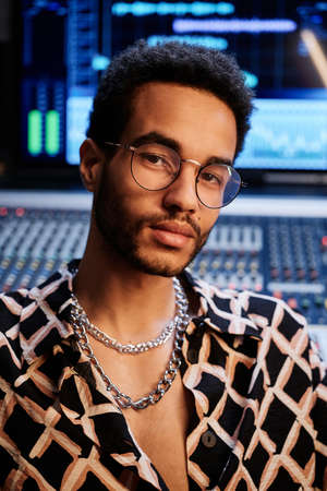Close-up of handsome young Black guy wearing fashionable shirt and eyeglasses working in recording studioの写真素材
