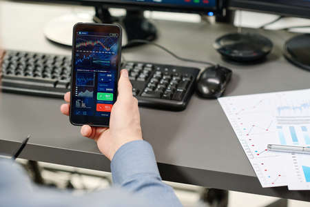 High angle shot of unrecognizable man working in stock trading industry watching charts and graphs...