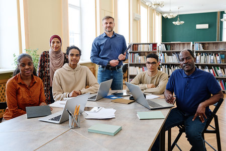 Group portrait of modern English language teacher and multi-ethnic immigrant students having class in library looking at cameraの写真素材