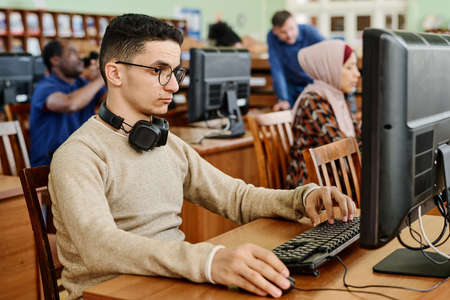 Group of ethnically diverse students sitting in modern university library working on computers