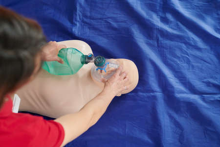 High angle view of paramedic demonstrating reanimation with artificial ventilation using oxygen mask on floor during trainingの写真素材