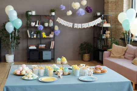 Image of holiday table served with desserts, cupcakes, donuts and other sweets preparing for birthday party at homeの写真素材