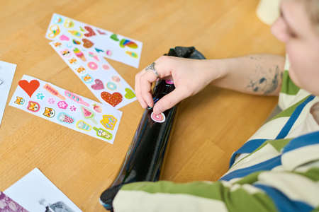 Above view of young female with physical disability putting handmade stickers on her myoelectric arm...