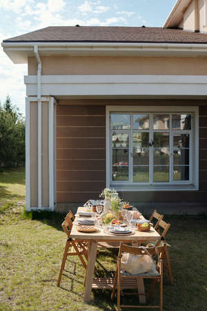 Served table with homemade food, drinks, wildflowers and other stuff prepared for outdoor party...