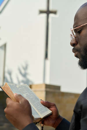 Close-up of African American preacher with open Bible reading verses while speculating about their meaning or preparing for sermonの写真素材
