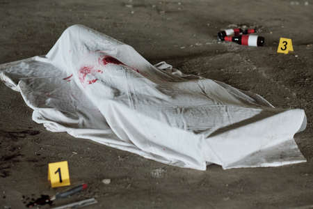 White sheet with stains of blood covering dead body shot with handgun or killed by knife or some...