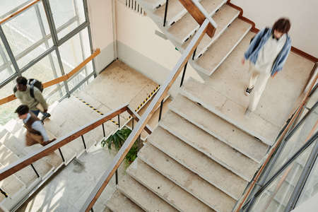 Students of modern university or other highschool moving along staircases while leaving for home or...