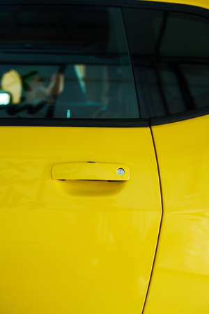 Part of door and window of modern electric car of yellow color standing in garage or gas station and waiting for repair or fuelingの写真素材