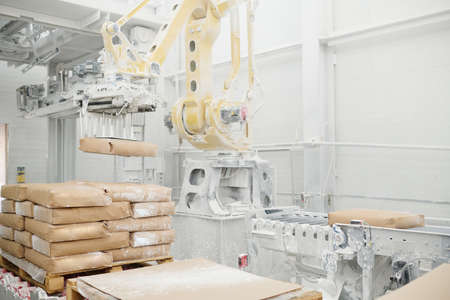 Huge hydraulic industrial machine lifting heavy packages and putting them on production line in workshop of modern factoryの写真素材