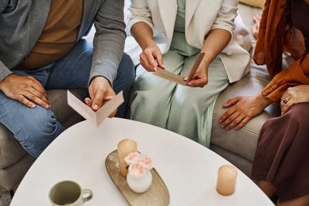 Mature couple in smart casualwear sitting on couch and reading invitation cards about forthcoming...