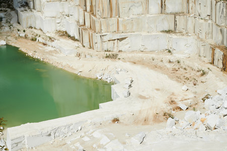 Part of surrounded territory of modern production factory at marble quarry with small pond by thick wall built up of huge white blocksの写真素材