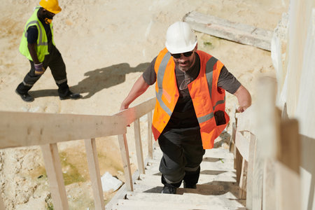 Middle aged male foreman or worker of industrial factory moving upstairs along staircase while...