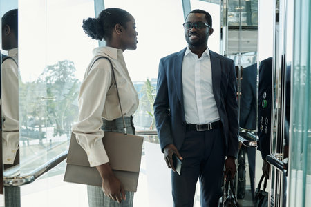Young elegant woman with handbag and her colleague in suit having discussion of some working points...