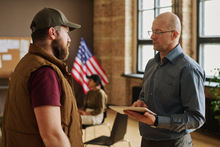 Confident mature counselor with tablet consulting one of his patients and answering his questions...