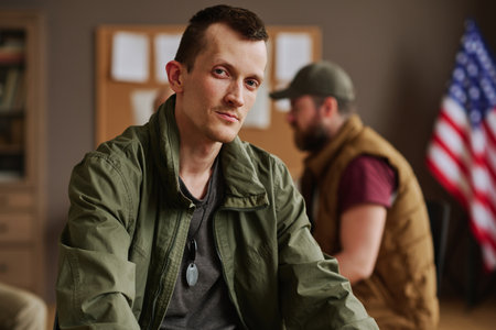 Young man in casualwear sitting in front of camera after psychological session against other...