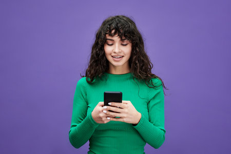 Young brunette woman in green pullover scrolling through online information or communicating in...