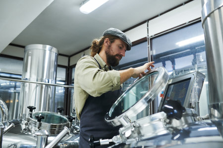 Brewery worker opening tank with fermenting beer to check if process going right