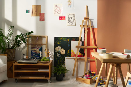 Part of studio of creative person with variety of items and equipment necssary for work, sketches on wall and small record playerの写真素材