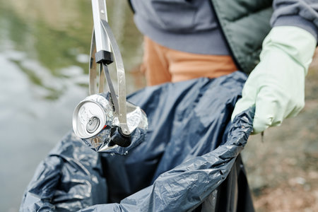 Closeup image of city park worker collecting garbage with special stickの写真素材