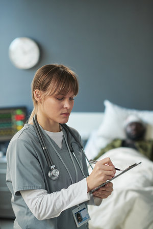 Young nurse in medical scrubs writing down medical prescriptions for patient of military hospital...