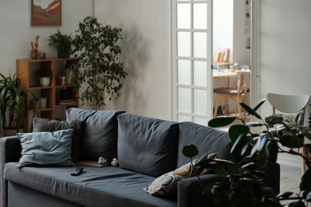 Part of interior of spacious living room of modern apartment with grey comfortable couch with...