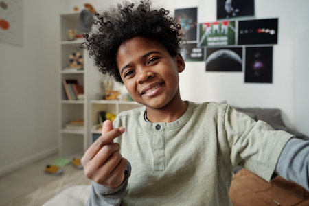 Happy African American schoolboy looking at camera while making selfie or communicating in video...