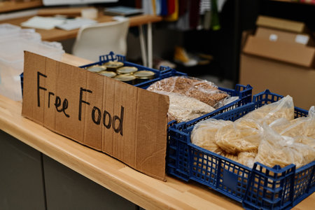 Close-up of plastic boxes containing packed cereal and other free food for homeless people on table in office of volunteering organizationの写真素材