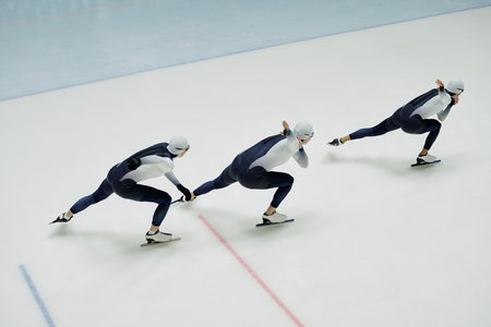 Above view of three young active athletes bending forwards while keeping left legs and right arms stretched during training on ice rinkの写真素材