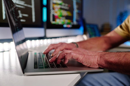 Focus on hands of aged male programmer typing on laptop keyboard while decoding data on screen in...
