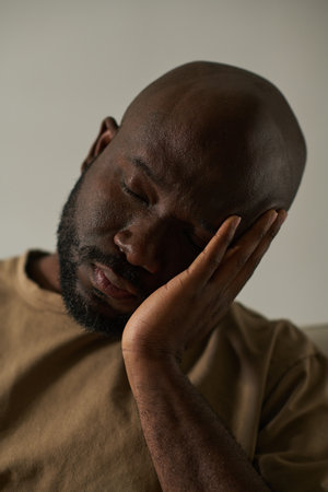 Vertical image of African American depressed man having headache isolated on grey backgroundの写真素材