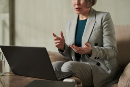Focus on hands of confident psychologit in grey formalwear explaining something to online patient...
