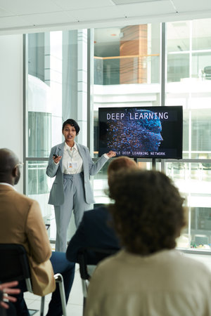 Long shot of young confident lecturer explaining point of presentation to audience while standing by interactive board during conferenceの写真素材