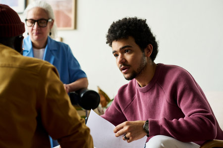Young confident multi-ethnic businessman with financial document looking at African American male colleague during discussionの写真素材