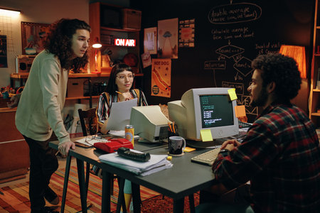Group of young people working over new project at table with computers in garage