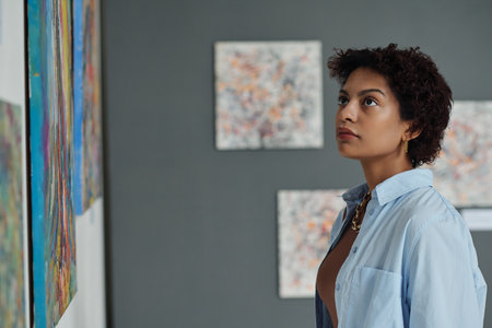 Young woman enjoying the modern art, she examining paintings on the wall in art galleryの写真素材