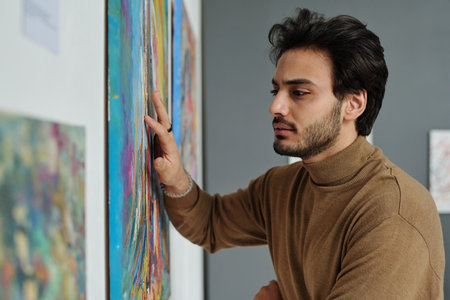 Art lover examining painting on the wall and enjoying modern art in art galleryの写真素材