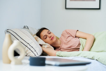 Young woman lying on bed and sleeping in her bedroom at homeの写真素材