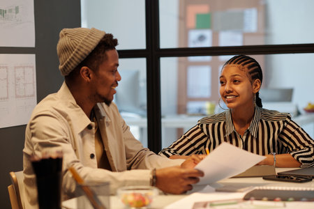 Young smiling businesswoman looking at male colleague during discussion of working points and making...
