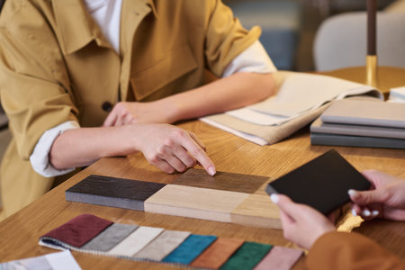 Hand of young female client pointing at sample of brown color while choosing new facing materials for design of her home interiorの写真素材