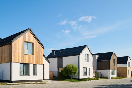 Perspective view of several small houses standing in row in rural environment against blue sky on sunny dayの写真素材