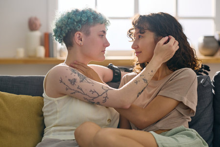 Side view of two young amorous girlfriends looking at one another while that with disability...