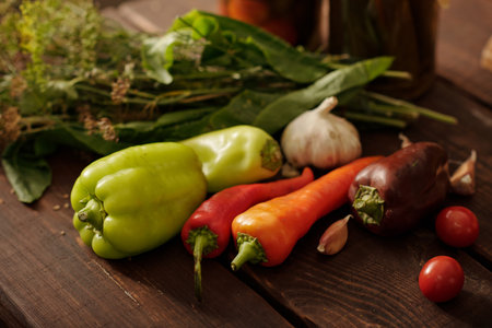 Fresh garden pepper of various sorts and colors, garlic and cherry tomatoes on wooden table prepared...